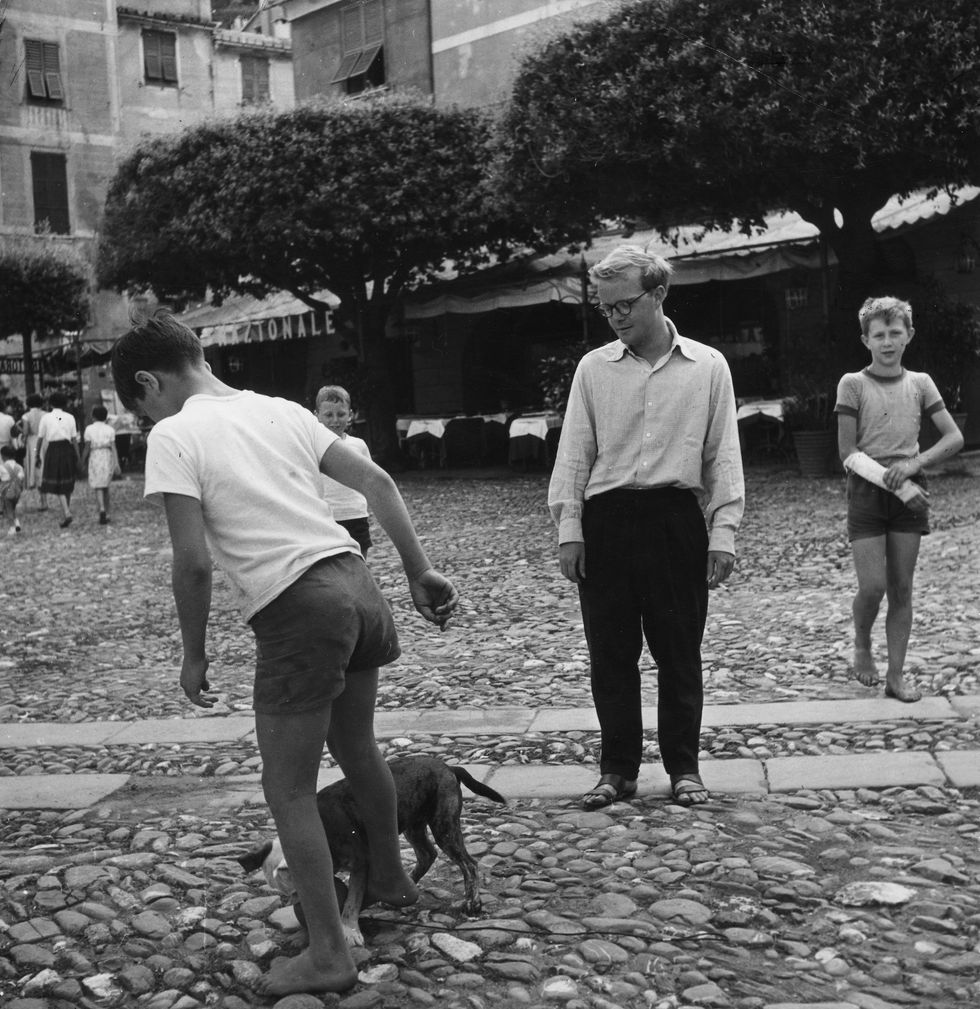 american writer truman capote watching a boy playing with his bulldog portofino, 1953