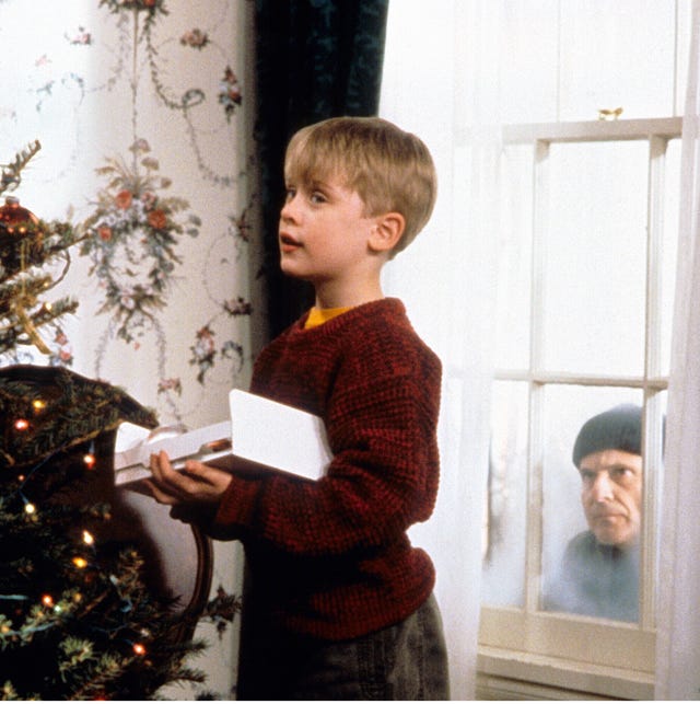 a boy holding a paper in front of a christmas tree