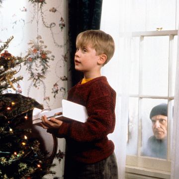 a boy holding a paper in front of a christmas tree