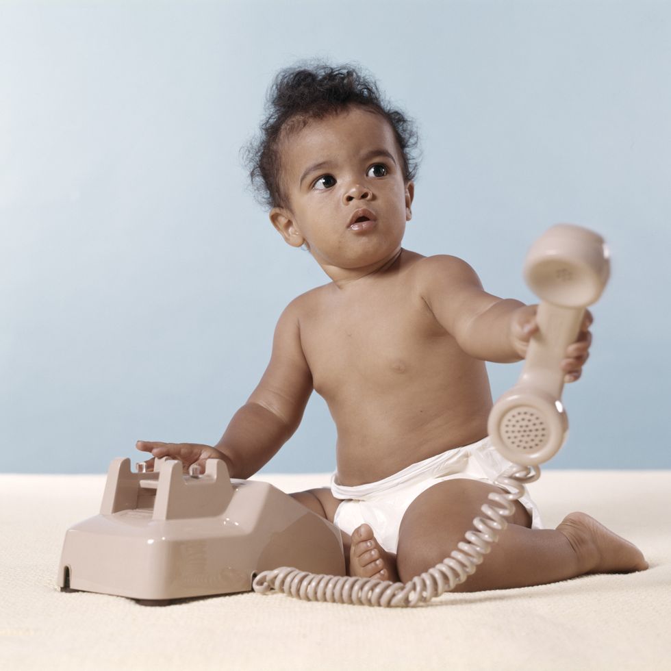 african american baby in diaper holding telephone