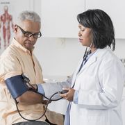 african american doctor checking senior man's blood pressure