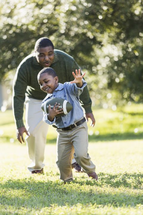 African American father and son playing football