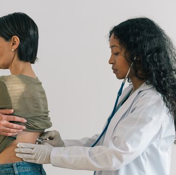 african american female doctor listening to mature patient heartbeat respiratory chest examination