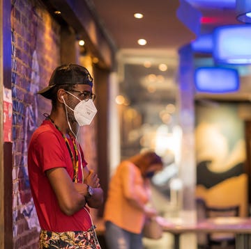 african american gentleman with a hat and glasses waits for his takeout food order during the covid 19 pandemic