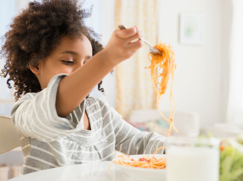 african american girl eating plate of spaghetti