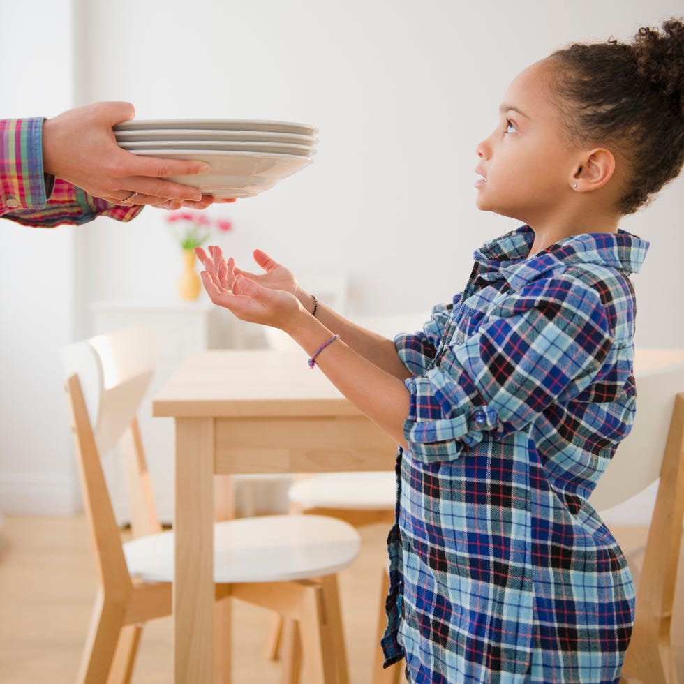 thanksgiving traditions   a black girl in a plaid shirt helping to set table