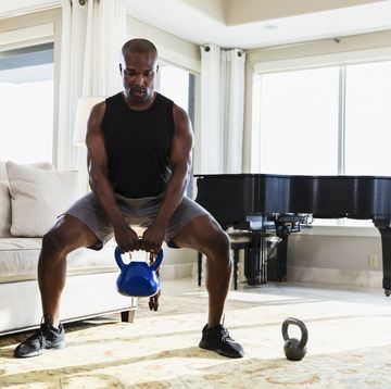 african american man exercising at home with kettlebells