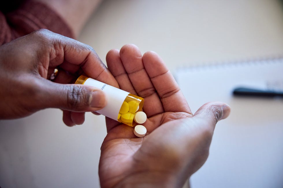 african american man pouring medications out of a bottle into his hand