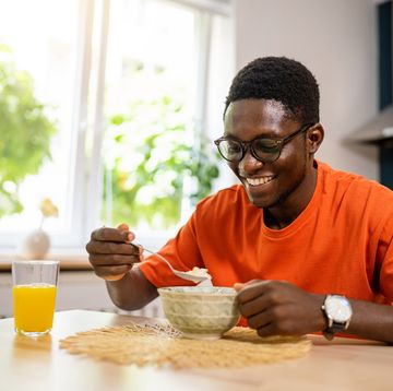 african american man, sitting for a dining table and eating oatmeal