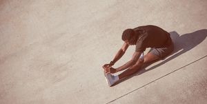 African American man stretches on pavement