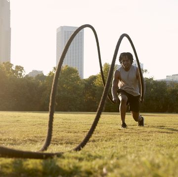 african american man working out with battle ropes in field