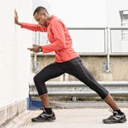 african american runner stretching against wall