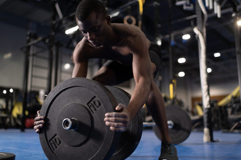 african american sportsman preparing barbell for exercising