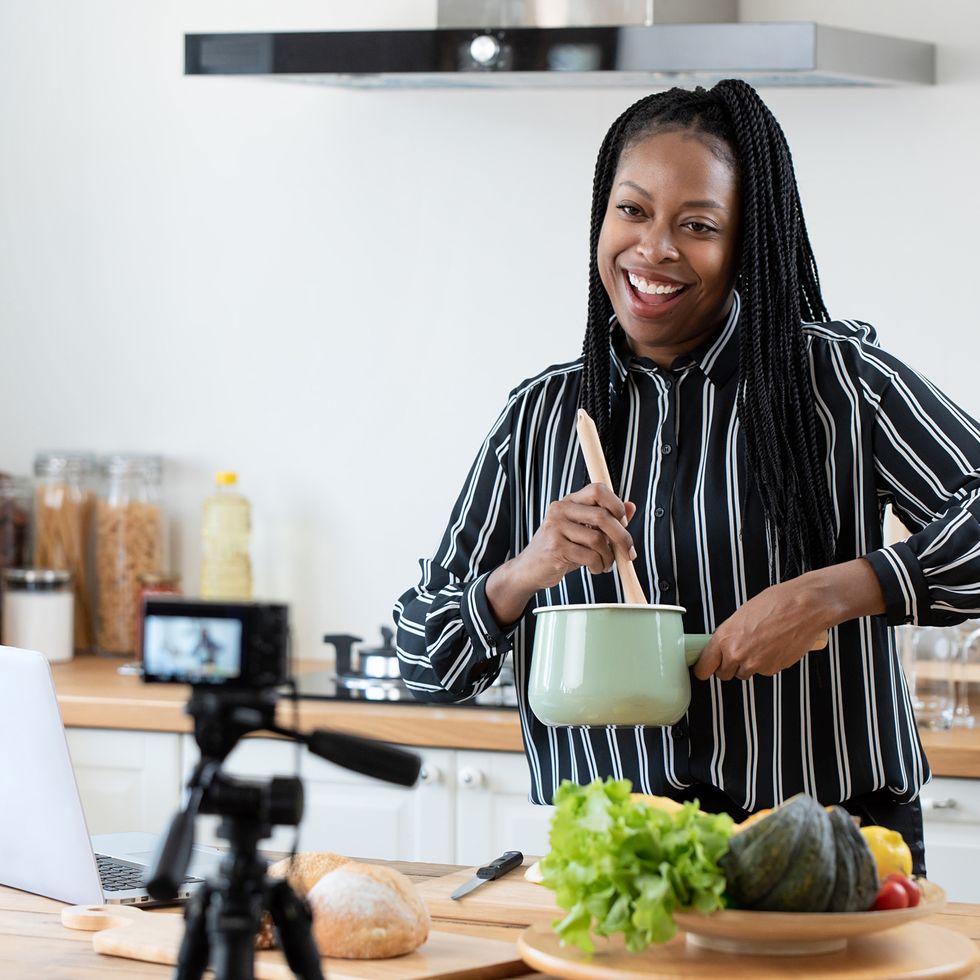 african american woman cooking vlogger recording video in kitchen at home
