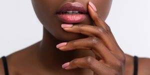 african american woman touching lips with shiny lip gloss
