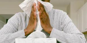 woman with box of tissue blows nose