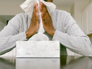 woman with box of tissue blows nose