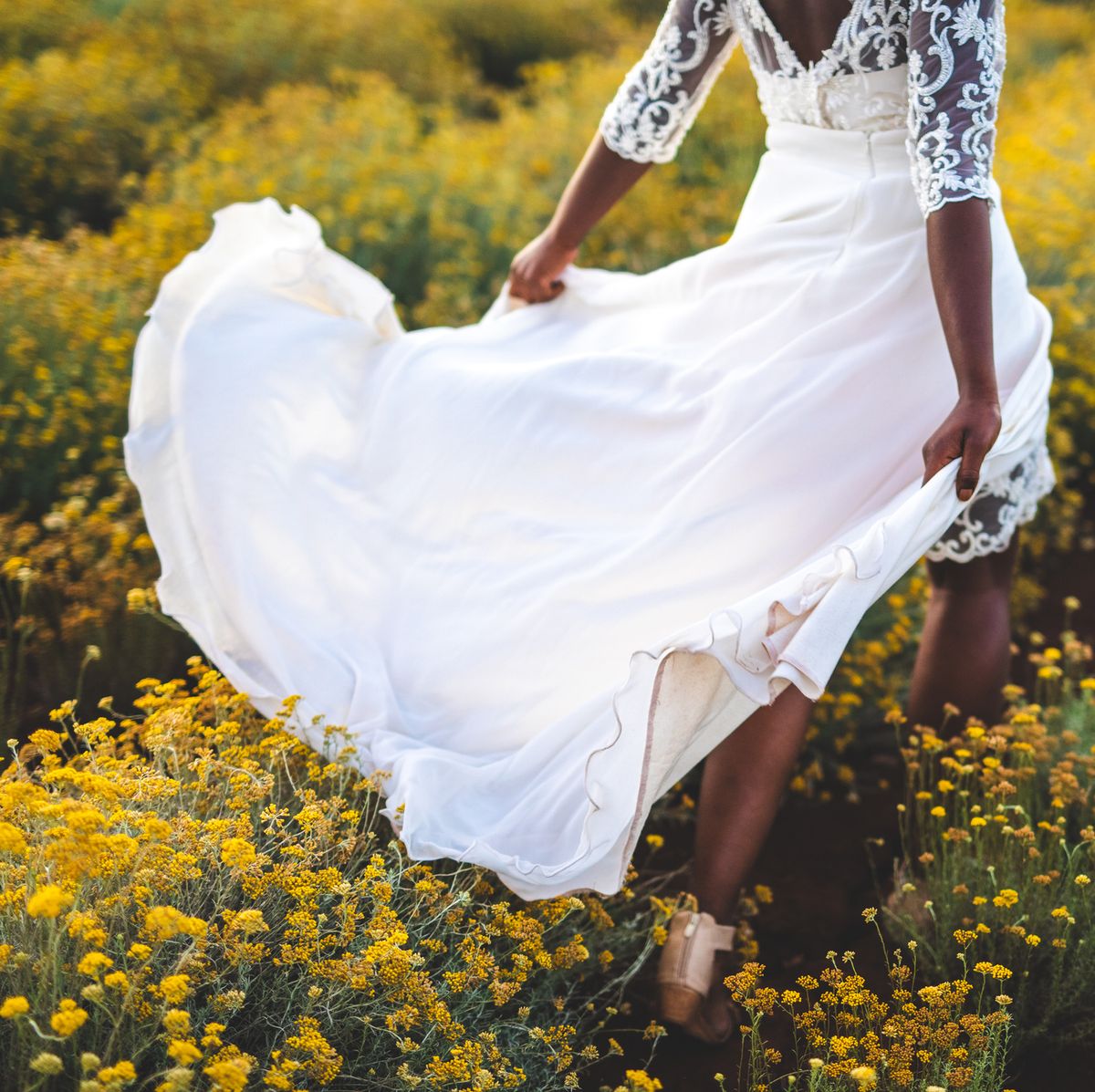 african bride in wedding dress running on meadow