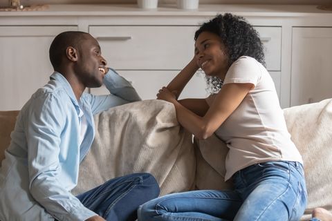 African couple in love sitting on couch chatting feels happy