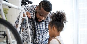 african father and daughter are fixed a bicycle together adjusting tightening a bicycle wheel at home