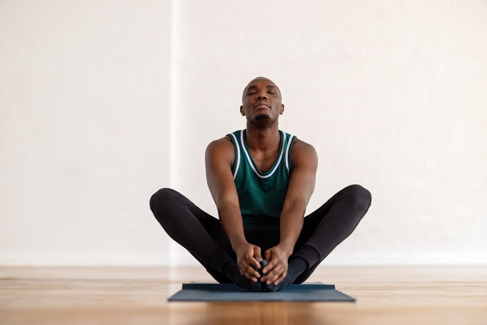 african man practice yoga in the butterfly position in yoga class