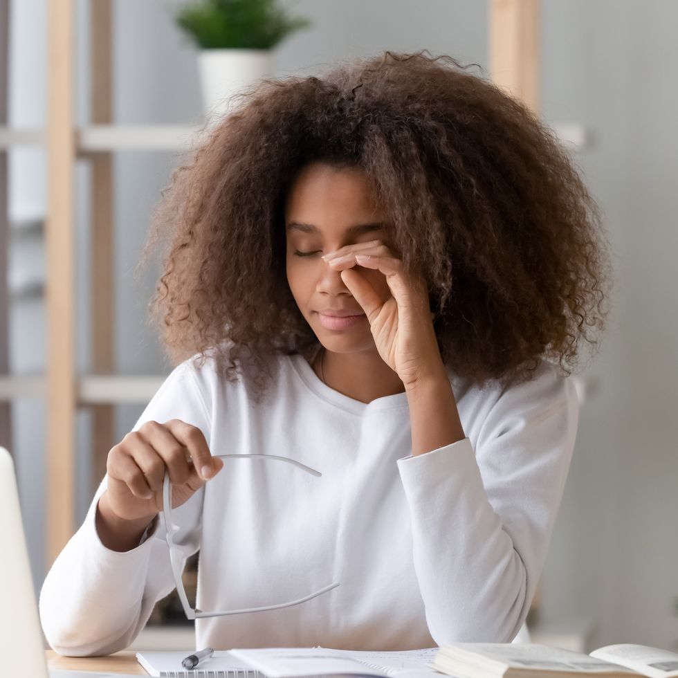 african teen girl rubbing eyes tired from computer holding glasses