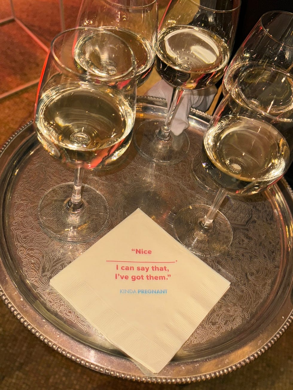 napkin with text placed beside glasses of white wine on a silver tray