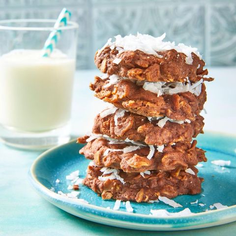 no bake chocolate oatmeal cookies with coconut flakes stacked up on blue plate