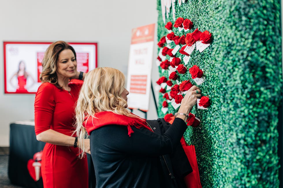 a woman holding a bouquet of red flowers next to another woman