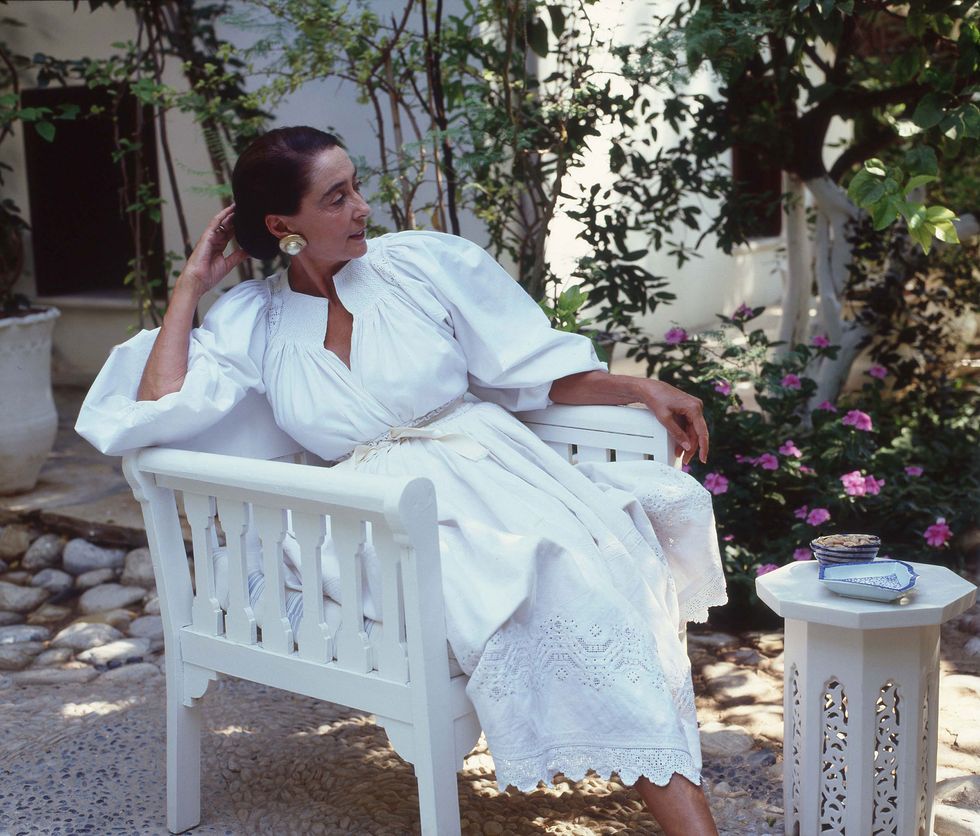 a person dressed in white reposing languidly on a bench