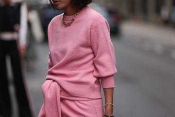 a woman wears two pink sweaters in a guide to the best fall sweaters of 2024