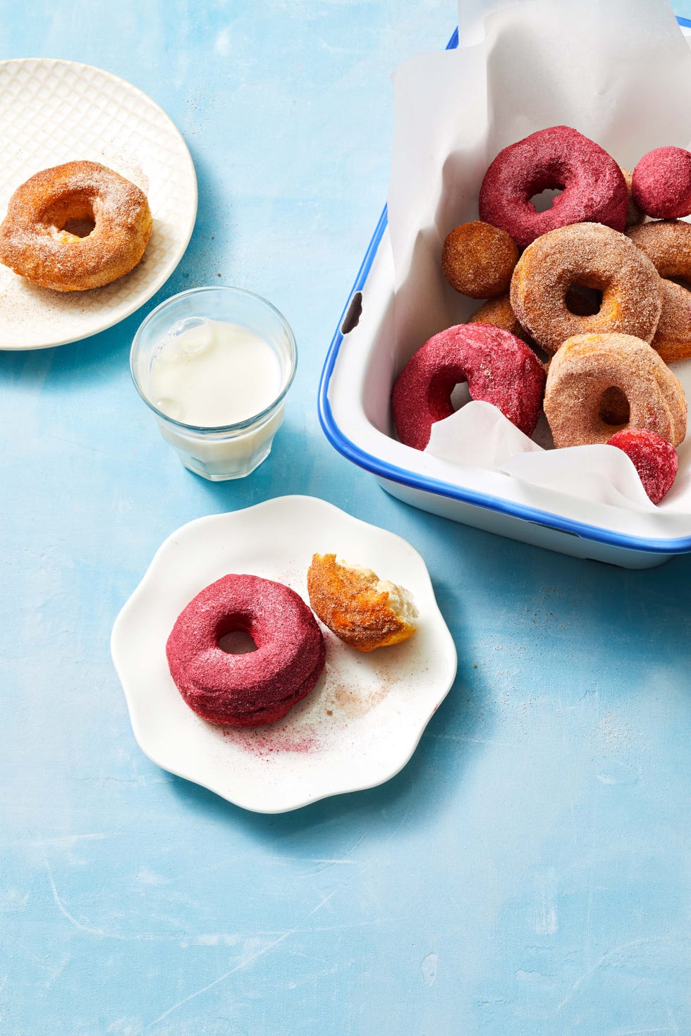 pink donuts on a white plate with a glass of milk on the side