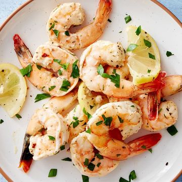 shrimp made in the air fryer on a plate topped with herbs and lemon wedges