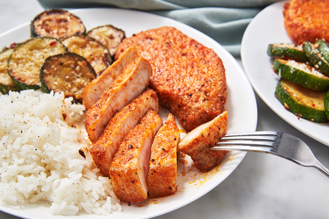 air fryer pork chops with white rice and roasted zucchini on a white plate