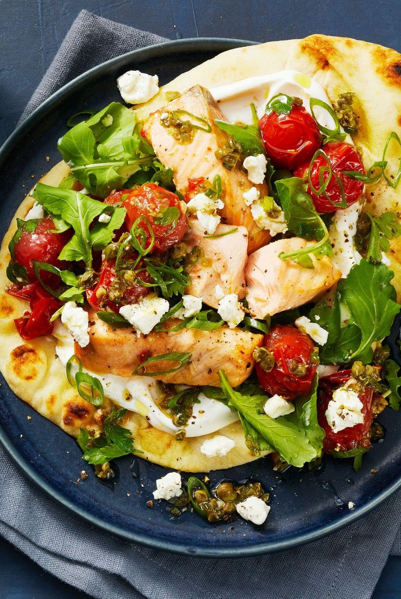 salmon flatbreads with tomatoes, cheese and greens on top