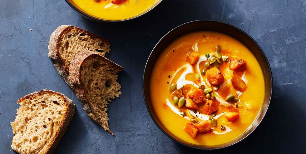 a bowl of butternut squash fall soup with slices of bread on the side