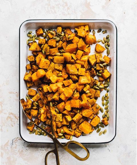 air fryer butternut squash on white tray with tongs and seeds