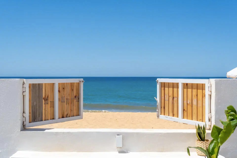 a white building with a beach and blue water
