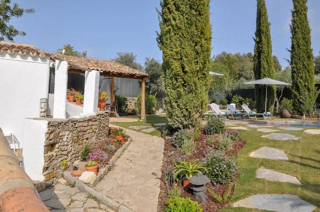 a patio with a stone wall and a stone patio with a stone wall and a building with trees