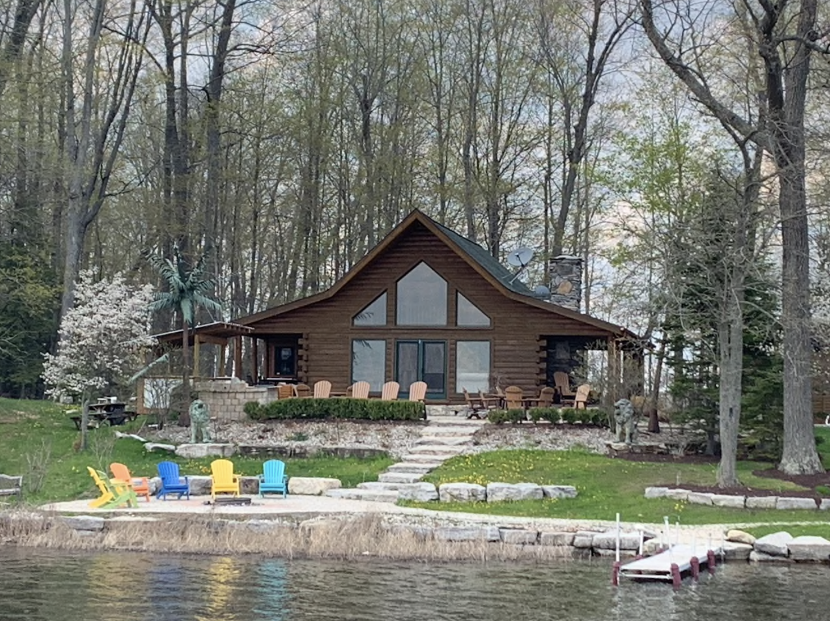 log cabin with colorful patio furniture in front of a lake