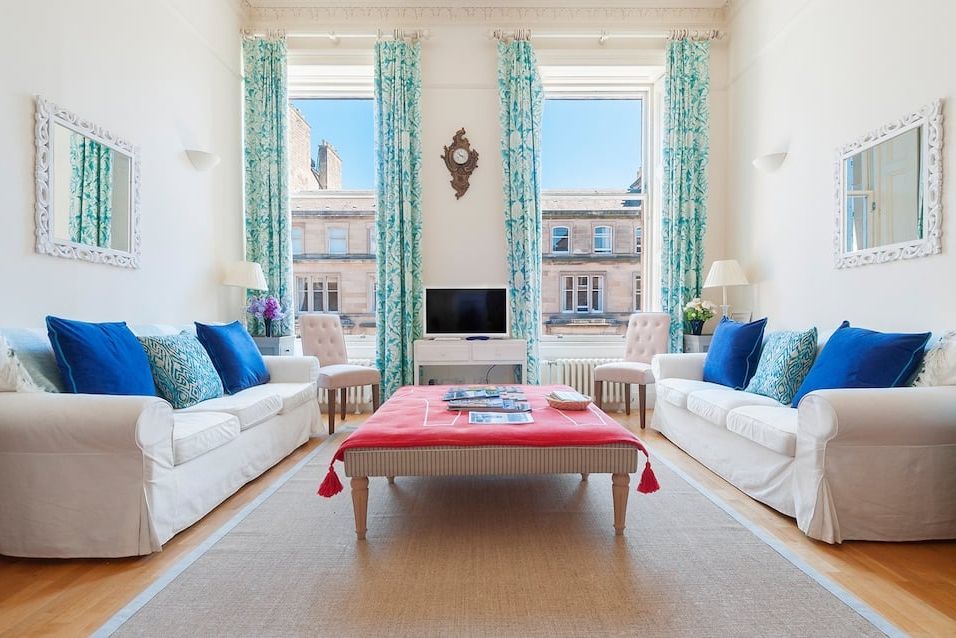 a living room with a red table and blue pillows