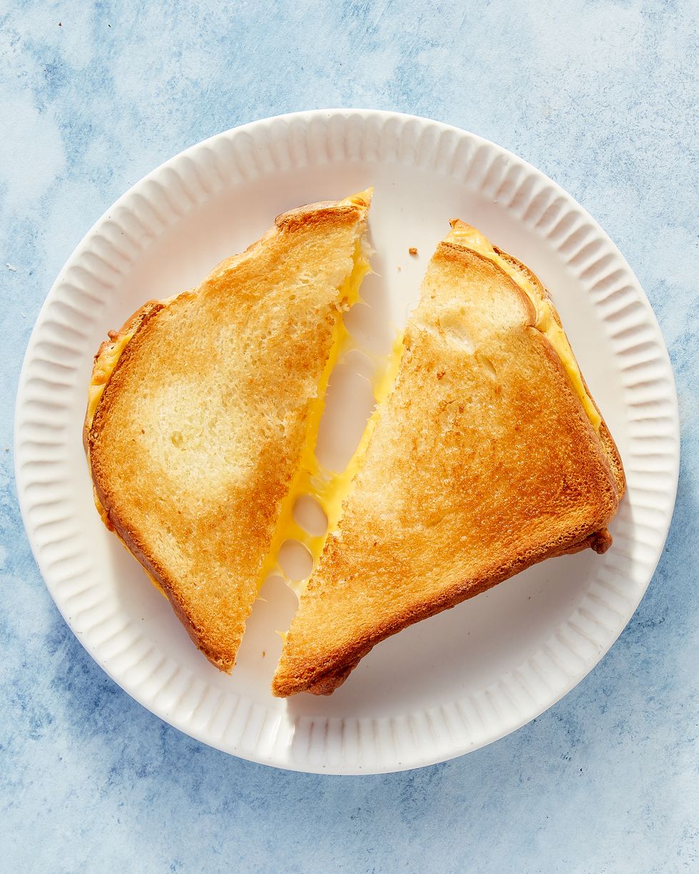 air fryer grilled cheese cut in half on a white plate on a blue marbled background