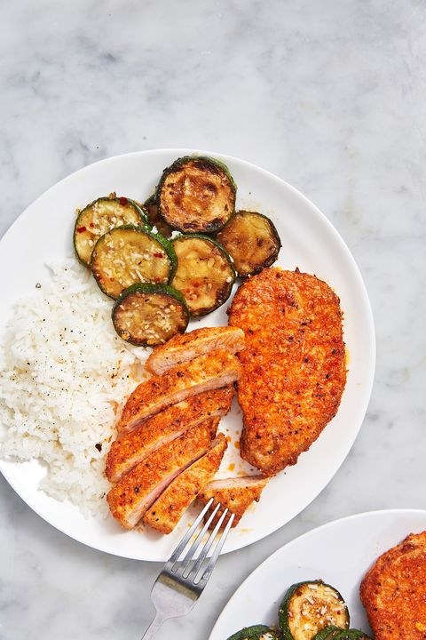 air fryer pork chops with white rice and parmesan zucchini slices on a white plate on a white marble background
