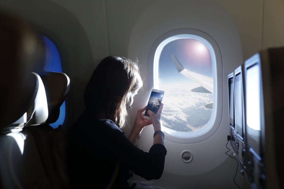 girl taking photo out of airplane window