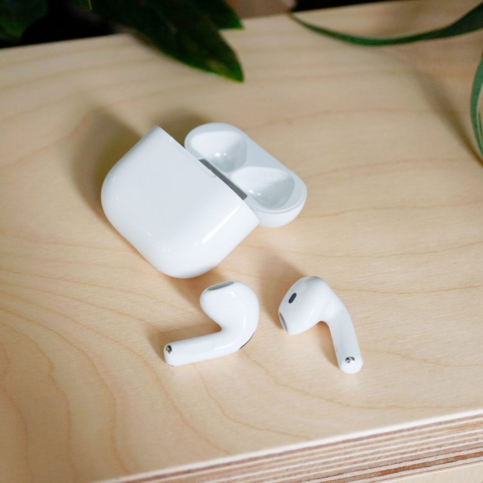 apple airpods 4 with their charging case on a wooden surface
