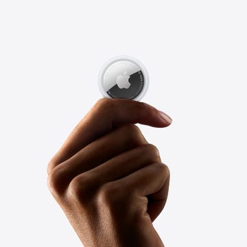 a hand holding an apple airtag
