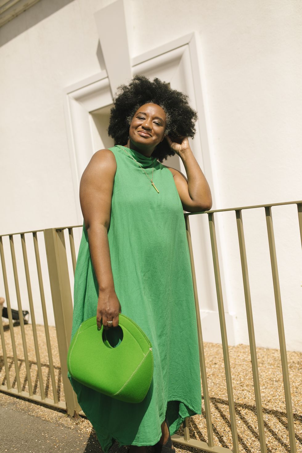 aja barber in a green dress, holding a green bag and smiling in the sun