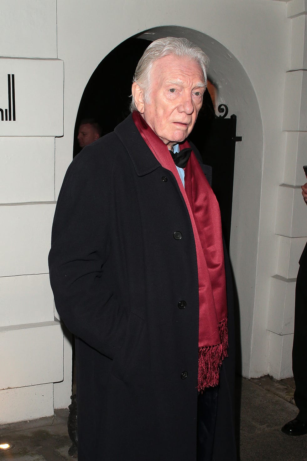 alan ford attending an event in february 2023, wearing a black coat and red scarf