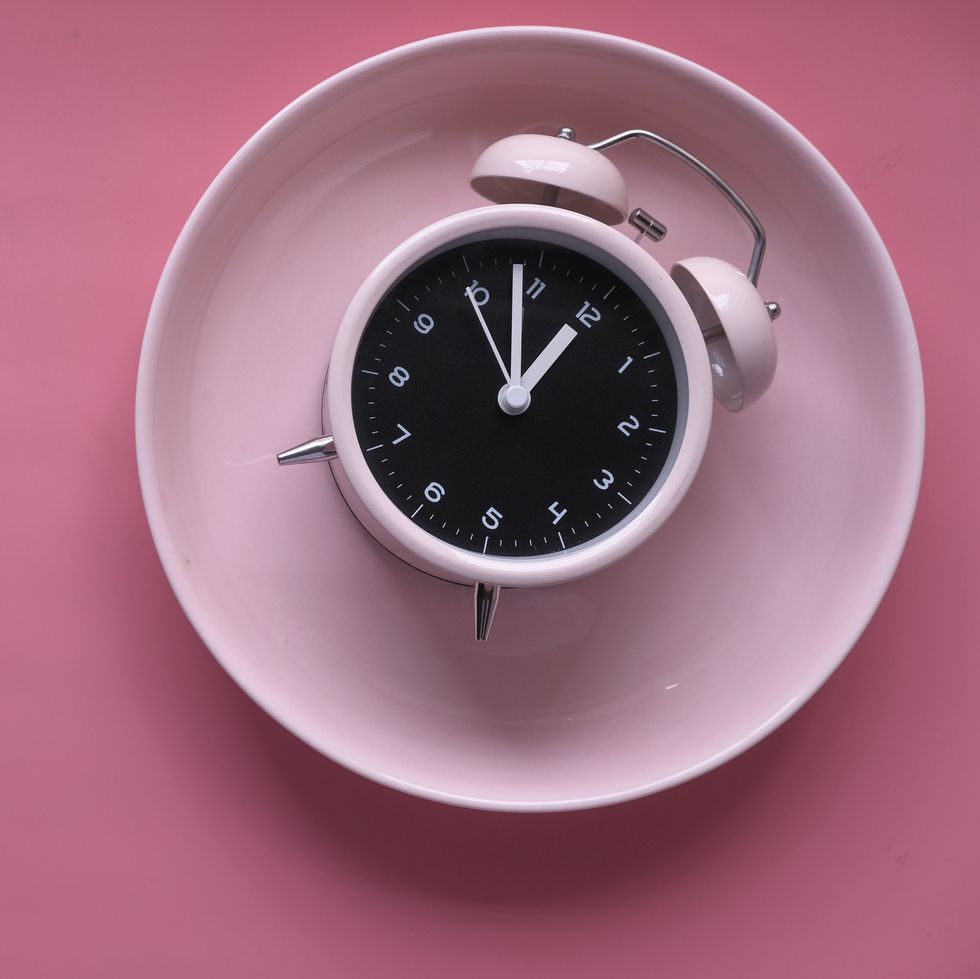 alarm clock on pink color plate on table