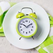 Alarm clock with bells on the plate, lunch time concept, top view with copy space